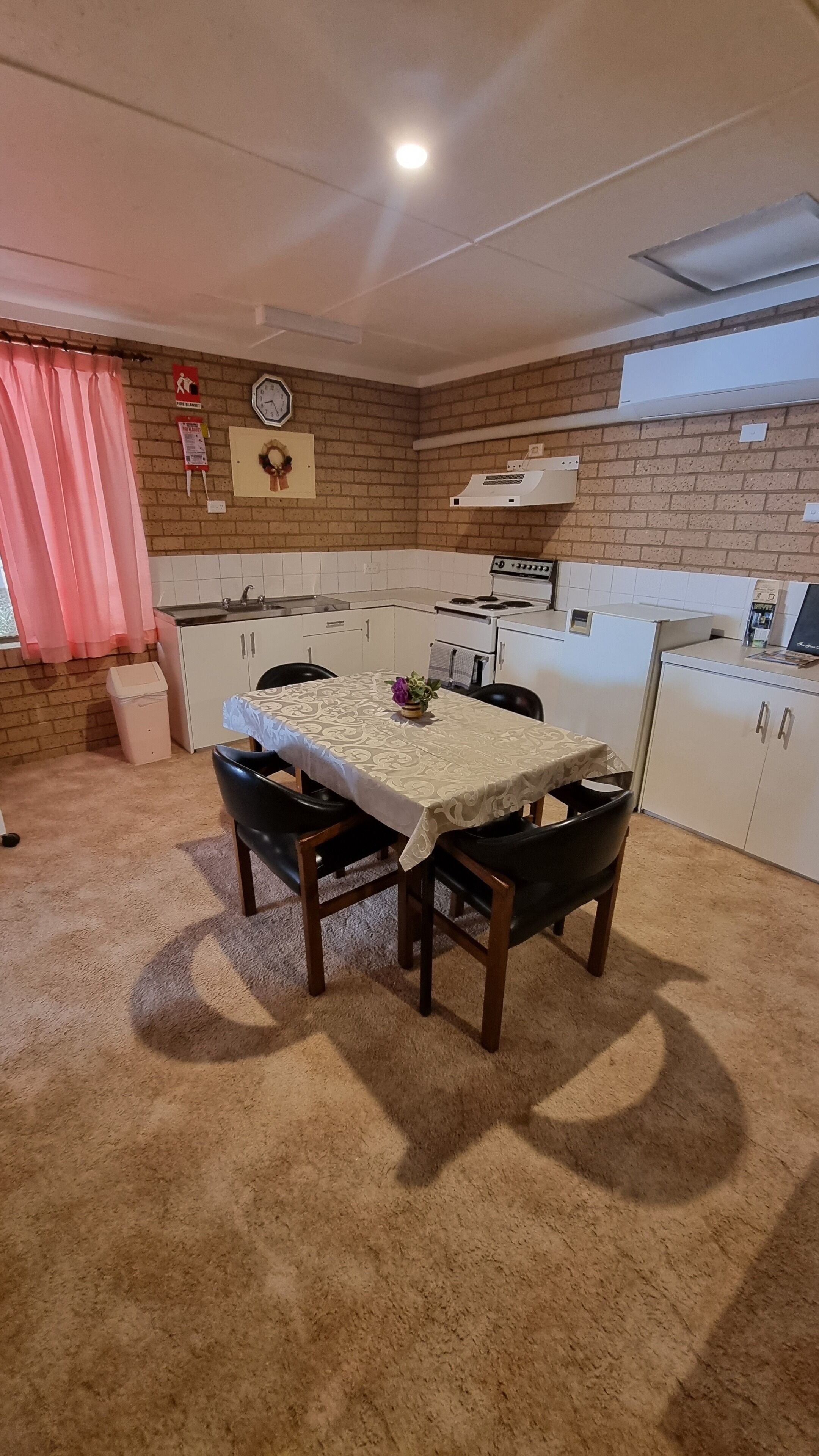 A compact kitchen with a dining table, chairs, and basic appliances.