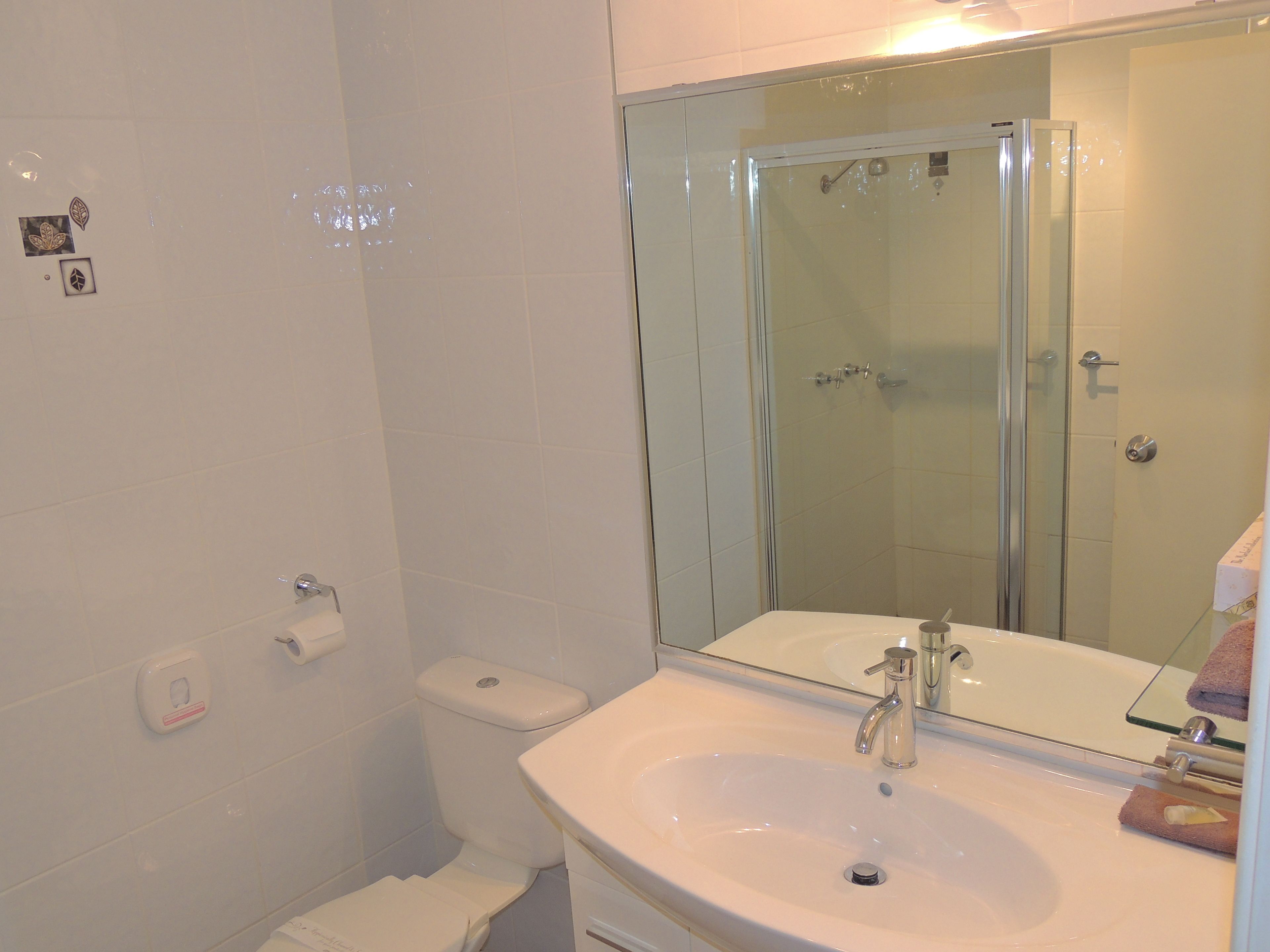 Un baño con lavamanos blanco, cabina de ducha de vidrio y un inodoro.