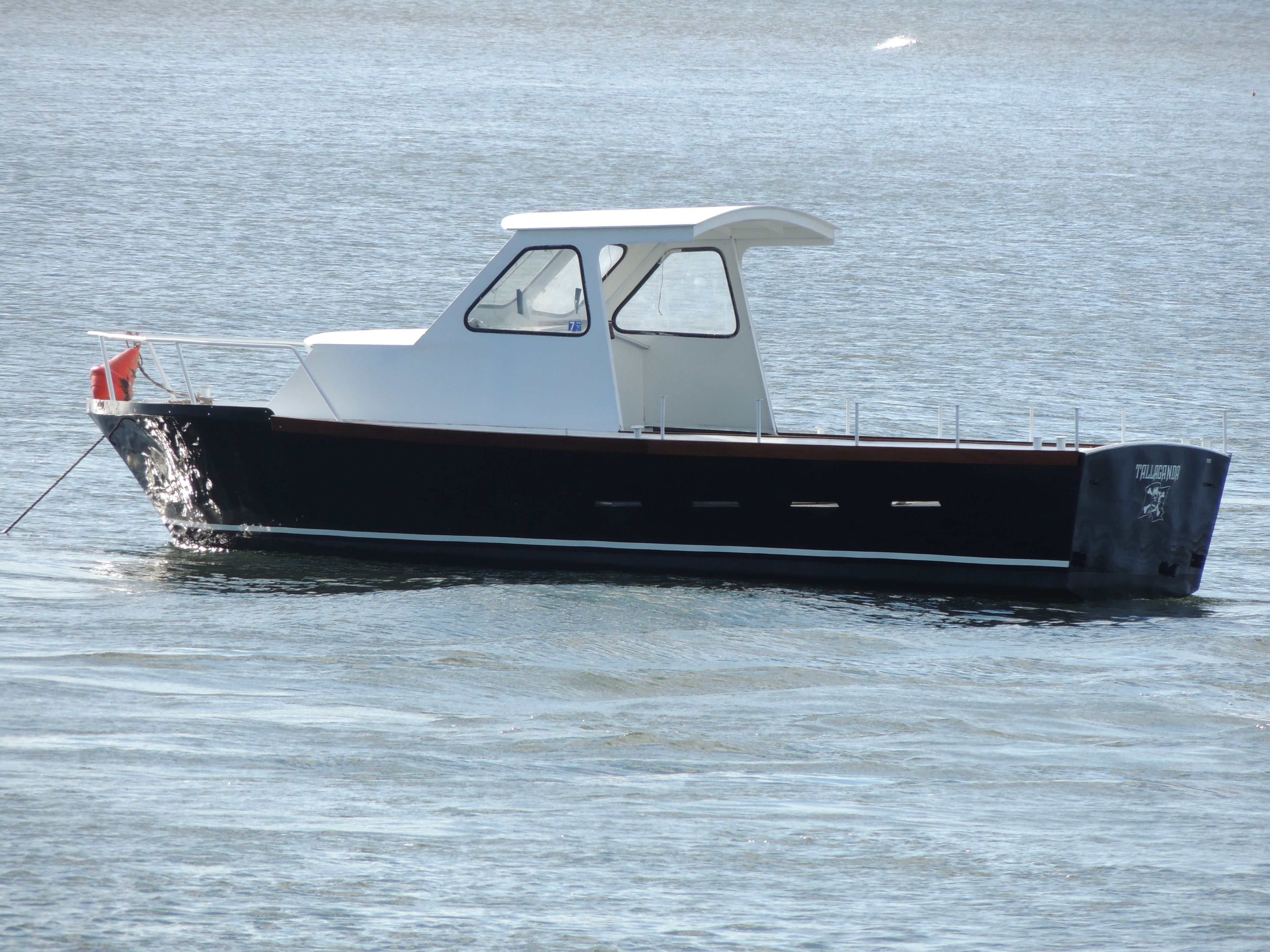A small, single-deck boat with a cabin and a cabin window, floating on calm water.