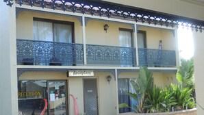 A two-story building with a reception area on the ground floor, featuring a balcony with ornate metal railings.