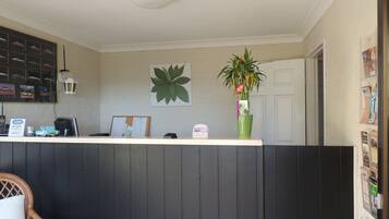 A reception area with a counter, a bulletin board, a potted plant, and a door.