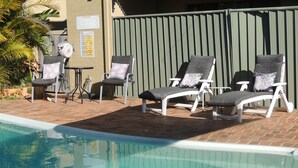 A poolside area with lounge chairs and a brick patio.