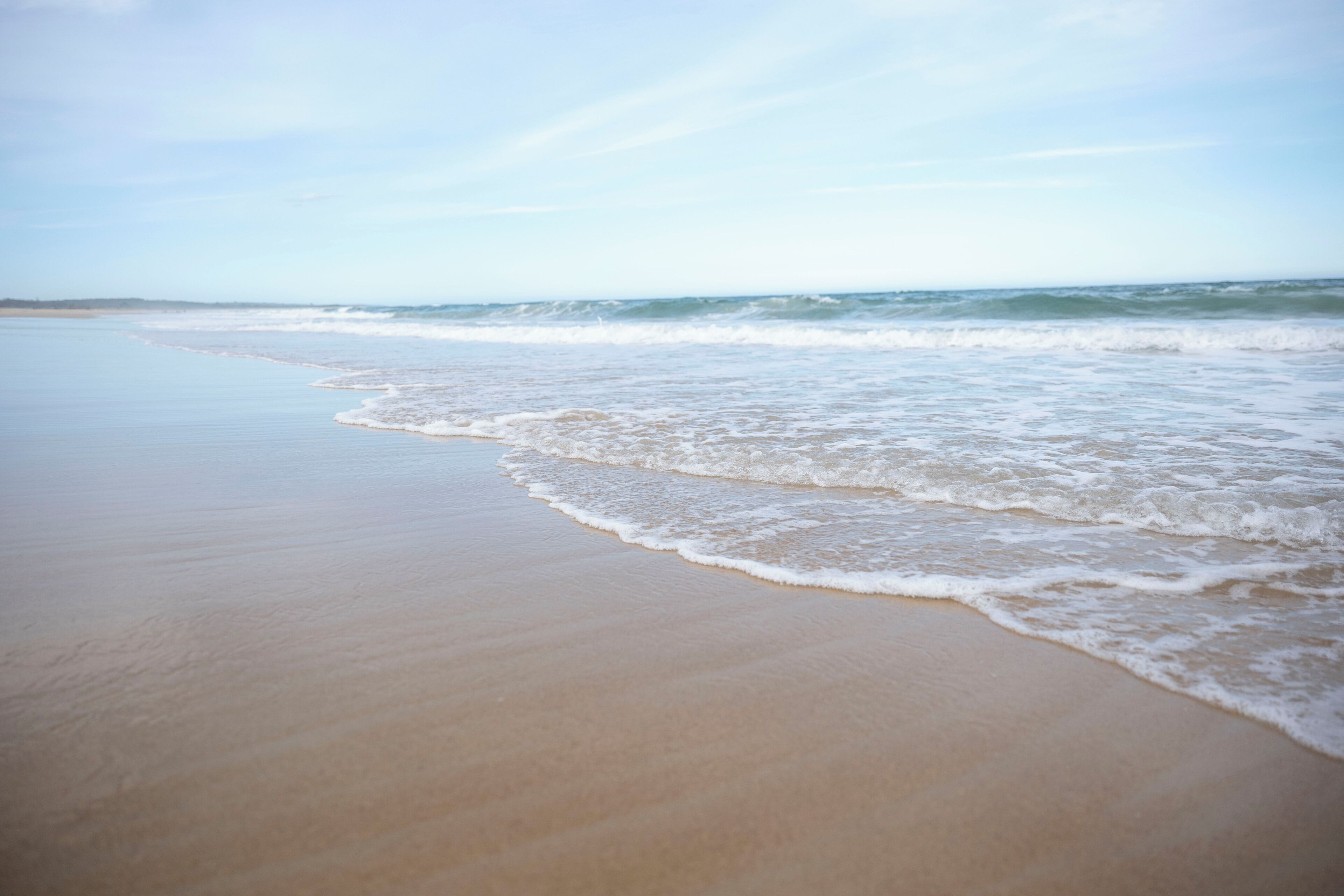A beach with gentle waves and a clear sky.