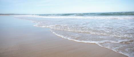 A beach with gentle waves and a clear sky.