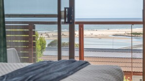 Una habitación con vistas a una playa y al océano a través de amplios ventanales.