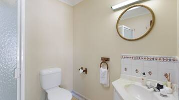 A bathroom with a toilet, sink, mirror, and towel rack.