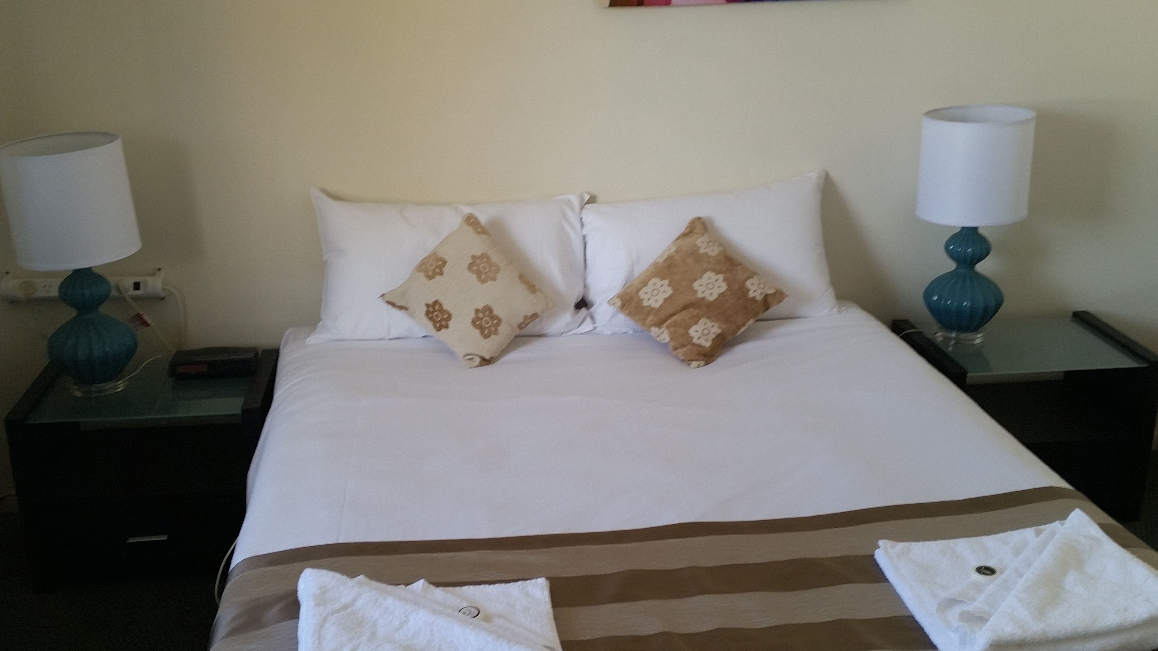 A hotel room with a bed, two nightstands, a lamp on each nightstand, and a towel on the bed.