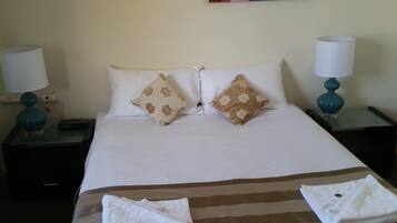 A hotel room with a bed, two nightstands, a lamp on each nightstand, and a towel on the bed.
