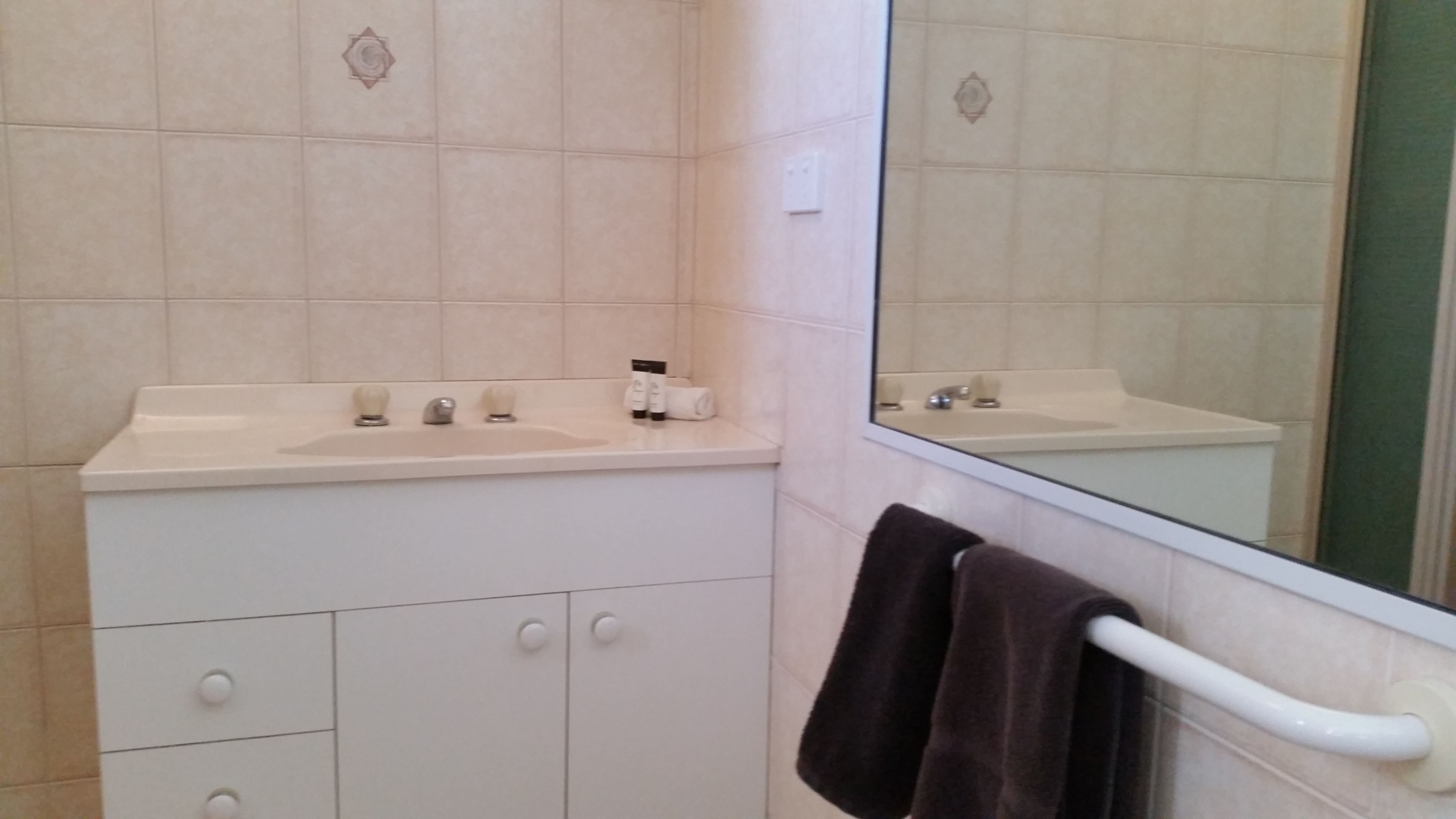 A bathroom with a sink, mirror, towel rack, and storage cabinet.