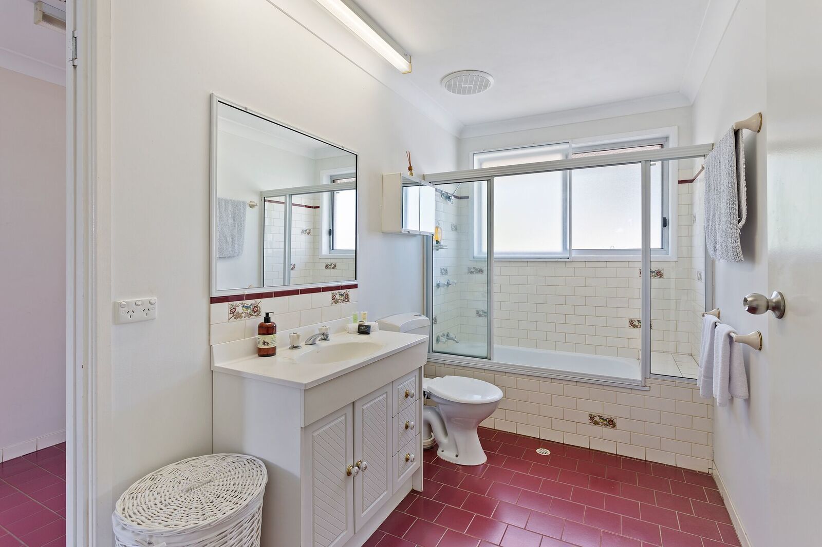Ein modernes Badezimmer mit einem weißen Waschtisch, einer Toilette, einer Duschkabine aus Glas und einem großen Spiegel.