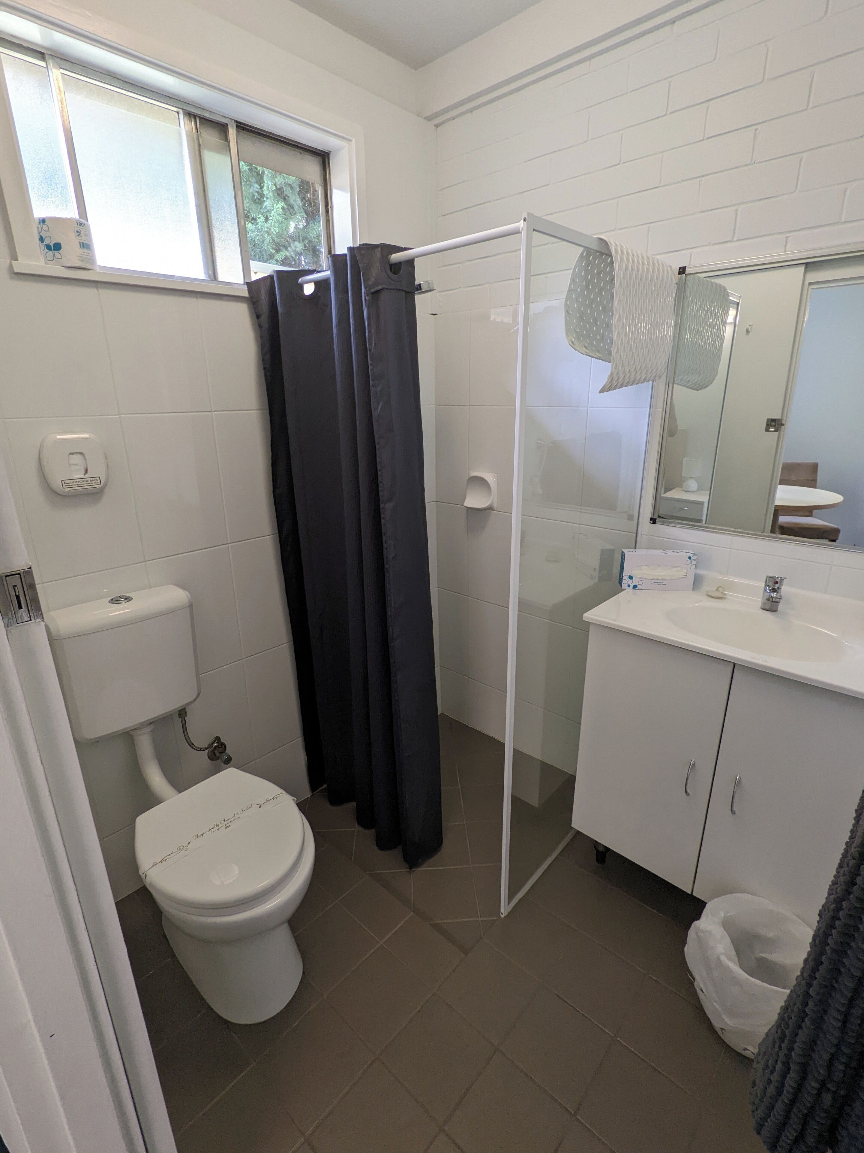 Un baño con inodoro, cabina de ducha, lavabo y espejo.