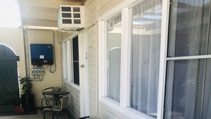 A covered patio area with a round table and four chairs, a potted plant, and a large window. - Kaputar Motel Narrabri (Narrabri)