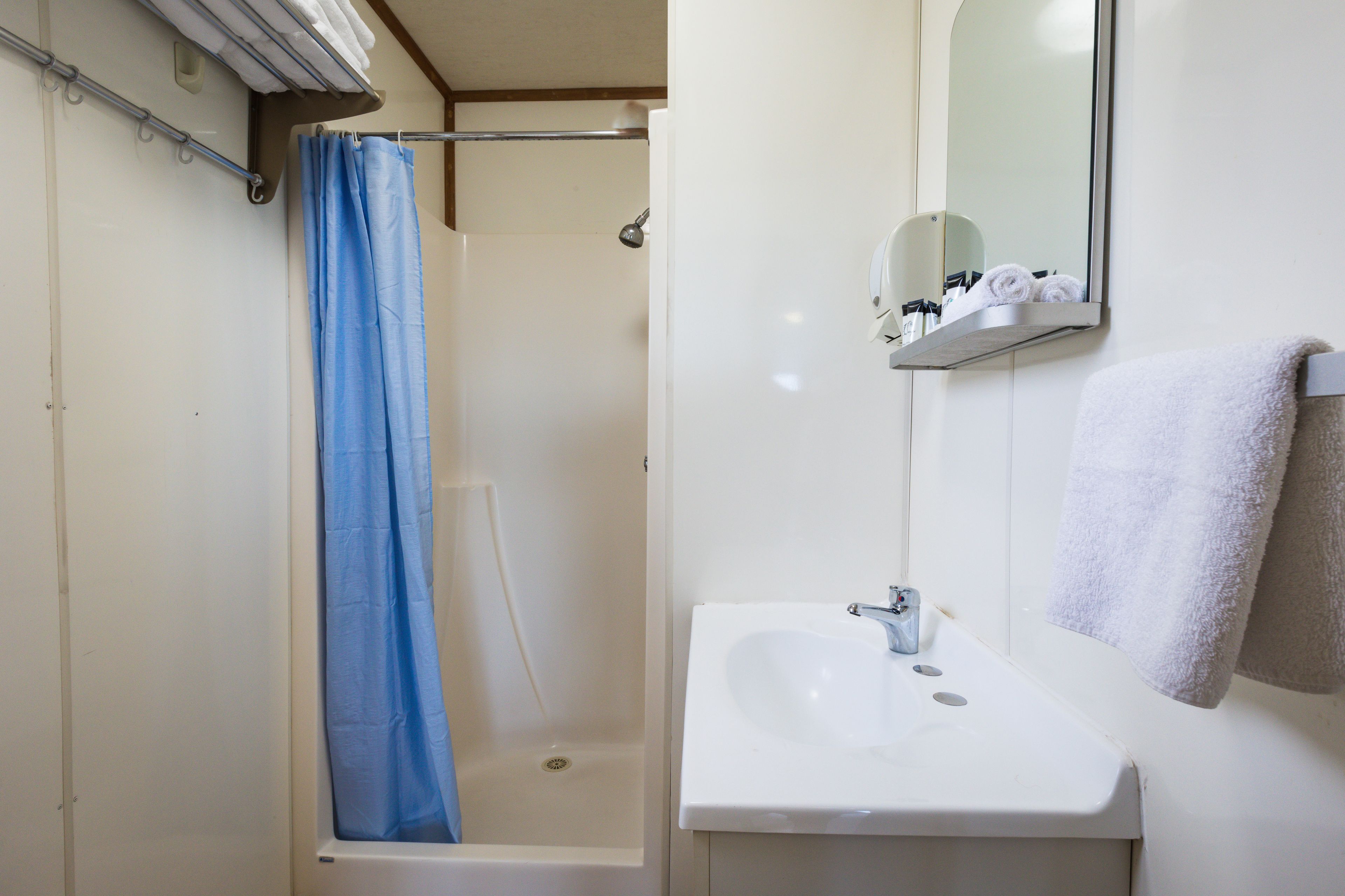A bathroom with a bathtub, a shower curtain, a sink, and a mirror.