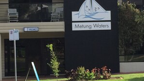 Un bâtiment avec une enseigne indiquant « Motel et appartements Metung Waters » et une autre enseigne indiquant « CHAMBRES LIBRES ».