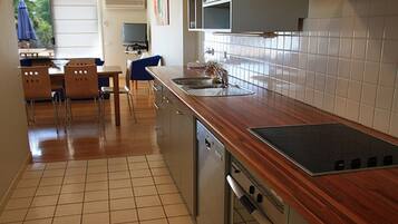 Une cuisine dotée de plans de travail en bois, d’un lave-vaisselle et d’un revêtement mural en carreaux.