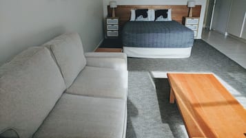 A bedroom with a bed, a sofa, and a wooden table.