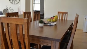 Una mesa de comedor con seis sillas de madera, un frutero y un reloj en la pared.
