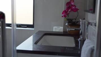 Un baño con lavamanos de encimera negra, un espejo y una orquídea en maceta.