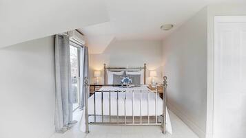A bedroom with a bed, bedside lamps, and a window with curtains.