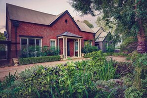 A brick house with a covered porch and a garden in front. - Evanslea Luxury Boutique Accommodation (Mudgee)