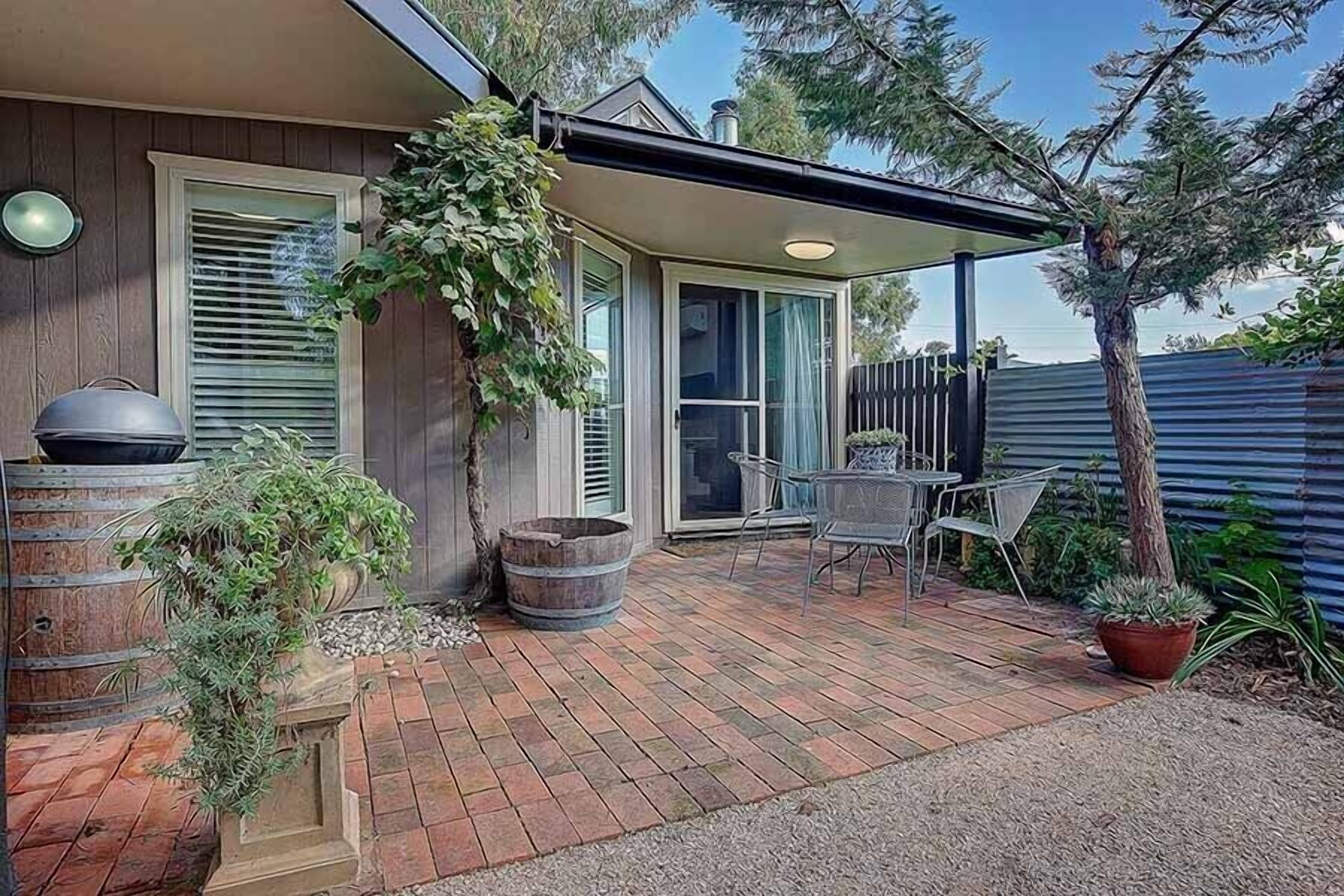 A patio with a barbecue grill, a table, and chairs.