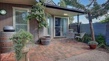 A patio with a barbecue grill, a table, and chairs.