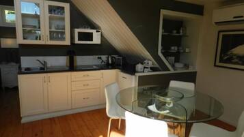 Una cocina moderna con armarios blancos, una mesa de comedor de vidrio y una silla blanca.