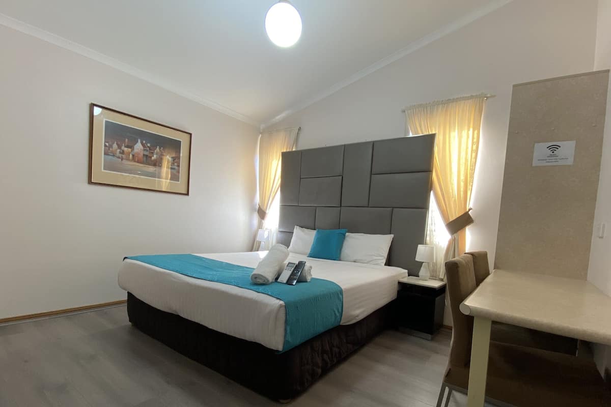 A hotel room with a bed, bedside table, and a small table.