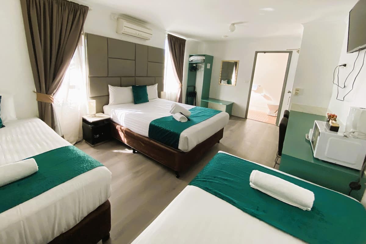 A hotel room with two beds, a bathroom, and a TV.