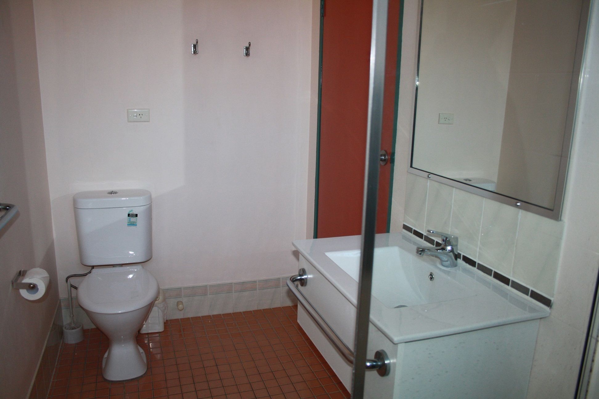 A small bathroom with a toilet, a sink, and a mirror.