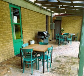 Enjoy al fresco dining under a shaded pergola with a barbecue grill and comfortable seating for four.