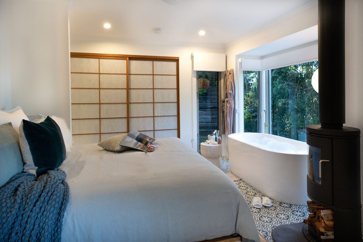 Un dormitorio moderno con una cama grande, un armario empotrado, una bañera y vistas al exterior.