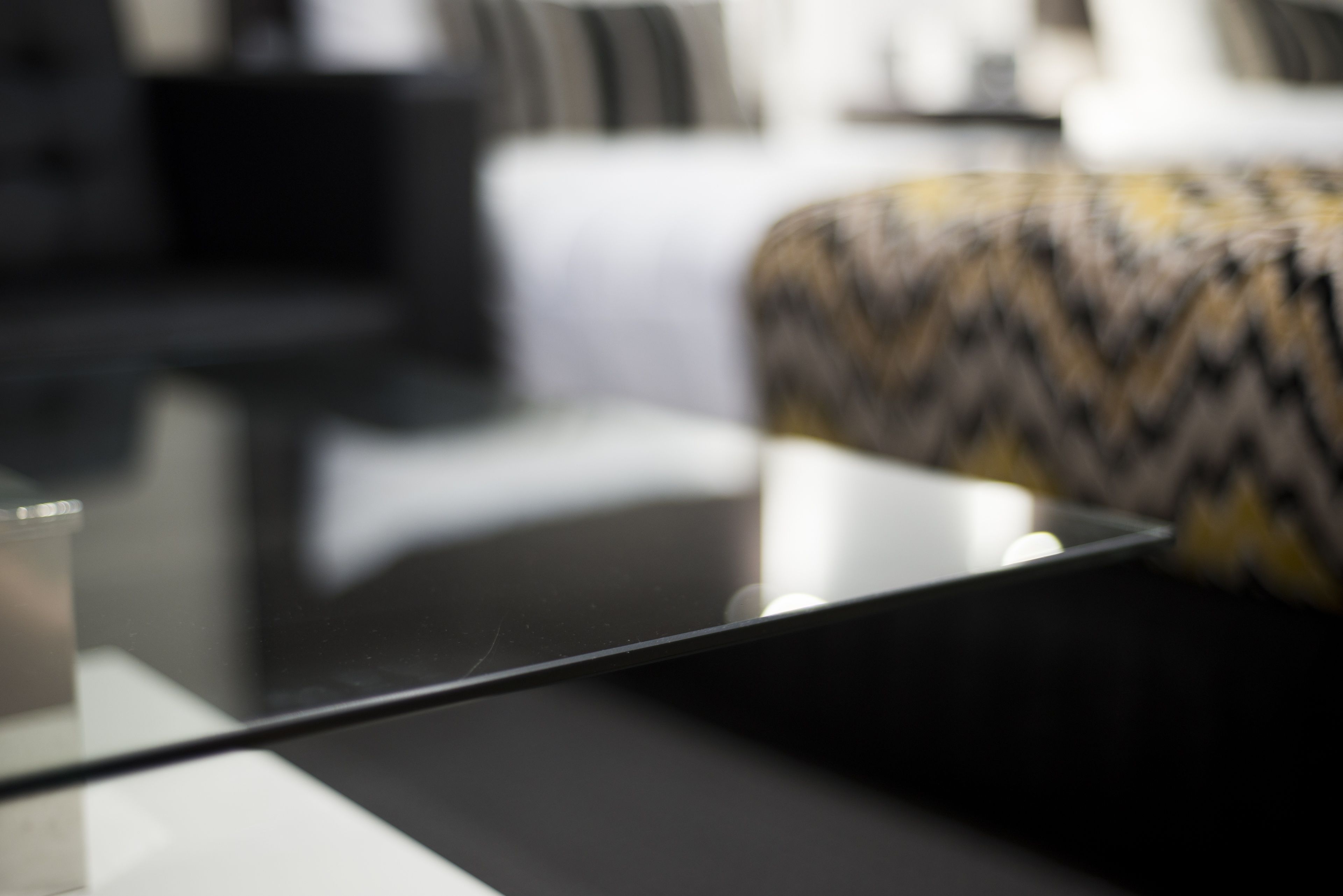 Una sala moderna con una mesa de centro de vidrio, un sofá estampado y un sillón negro.