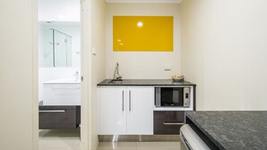 A modern kitchen with white cabinets, a black countertop, and a microwave.