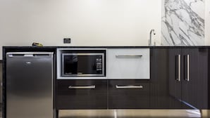 A modern kitchen with a built-in dishwasher, microwave, and dark wooden cabinets.