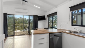 Una cocina moderna con lavavajillas, encimera de madera y puerta corrediza de vidrio que da a un balcón.