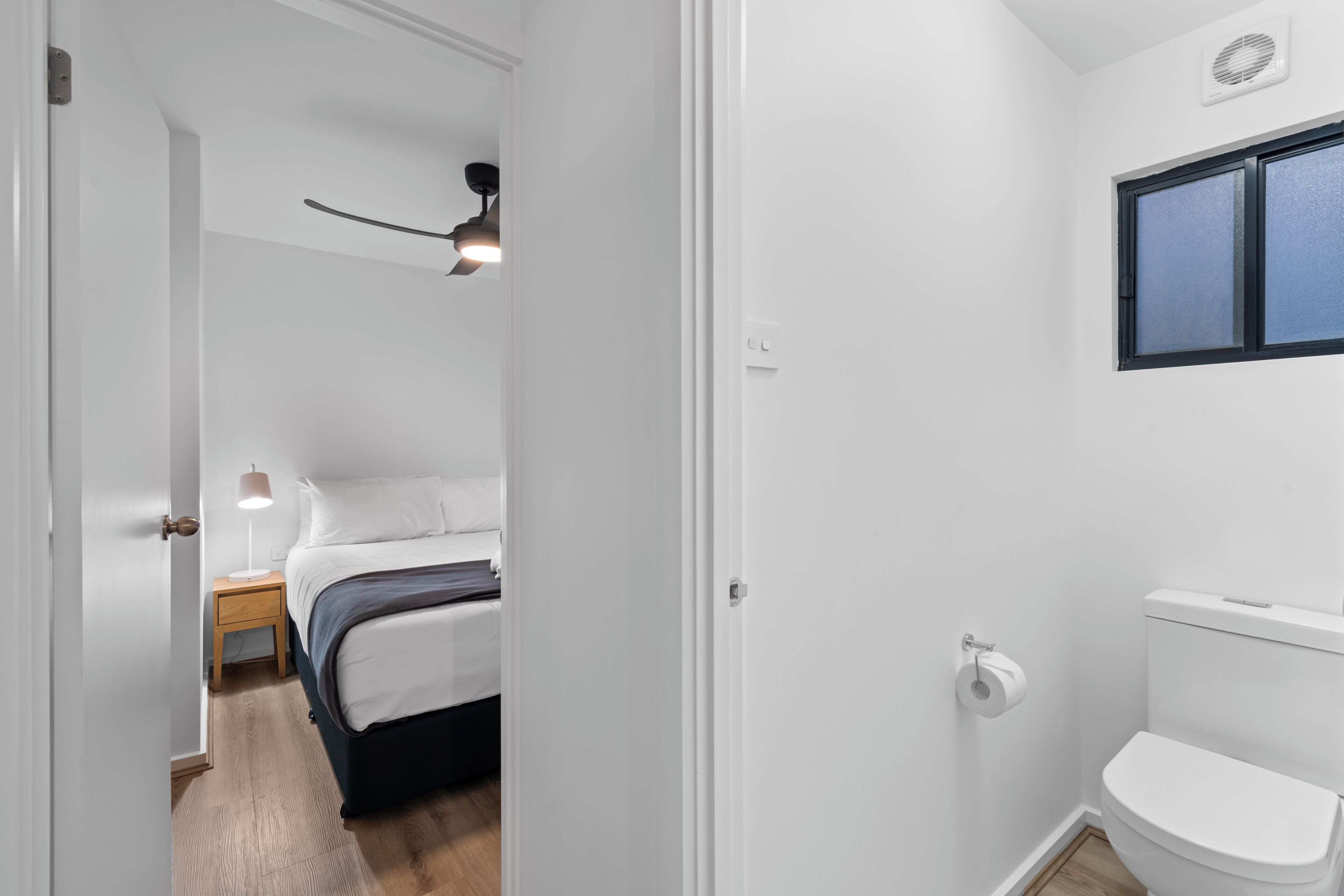 Ein Schlafzimmer mit Bett, Nachttisch, Lampe und Deckenventilator.