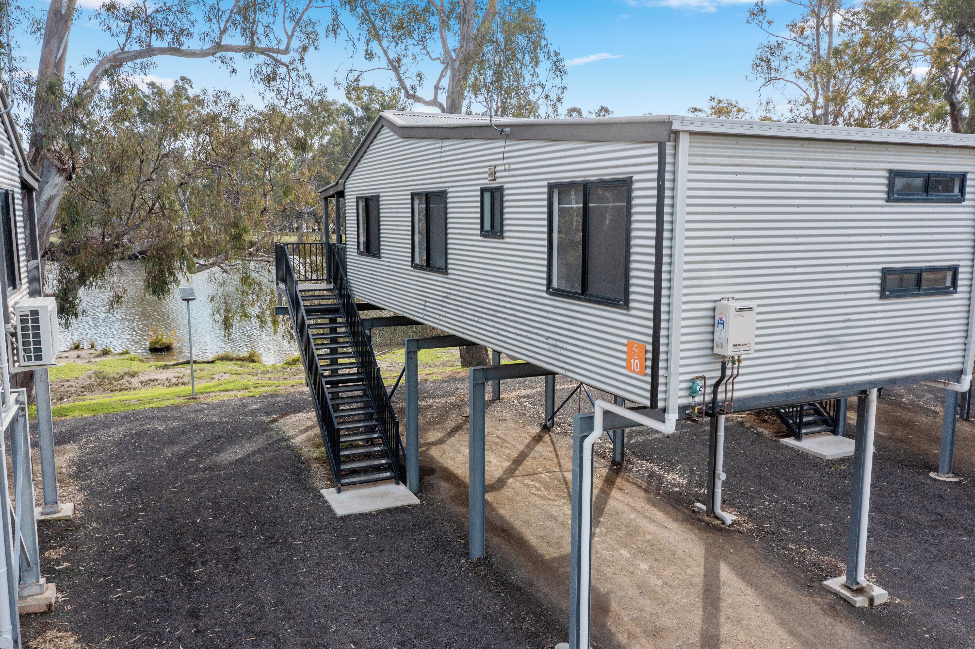 A mobile home with a small deck and a staircase leading to a covered area.