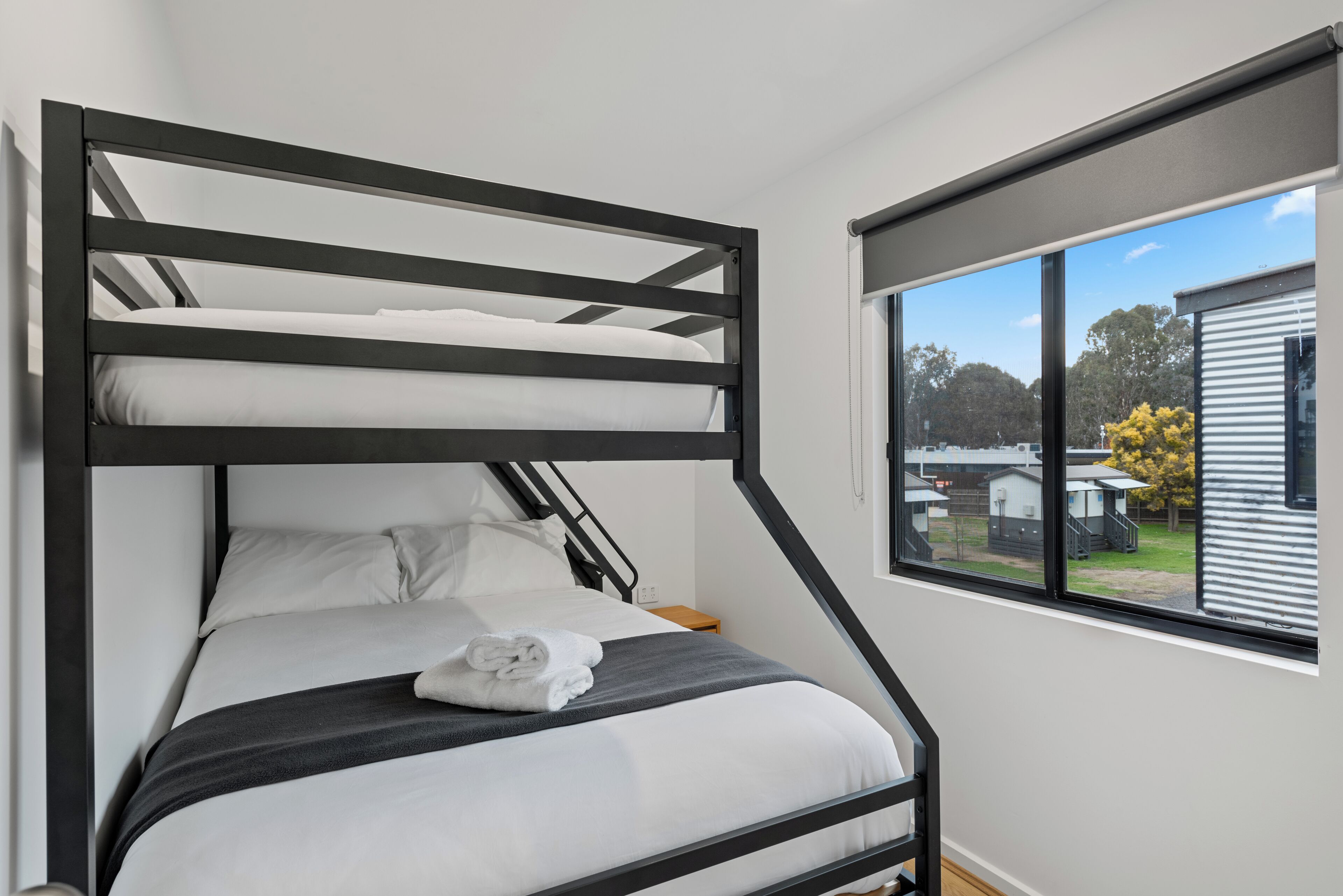 A bunk bed with a view of a residential area through a window.