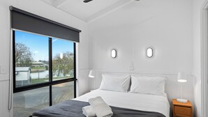Habitación de hotel moderna con una cama grande, dos lámparas de noche y vistas al exterior.