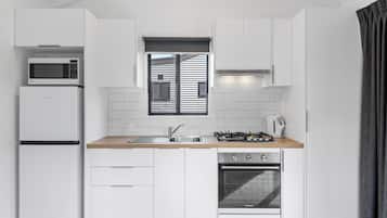 A modern kitchen with white cabinets, a microwave, a refrigerator, a sink, a stove, and an oven.