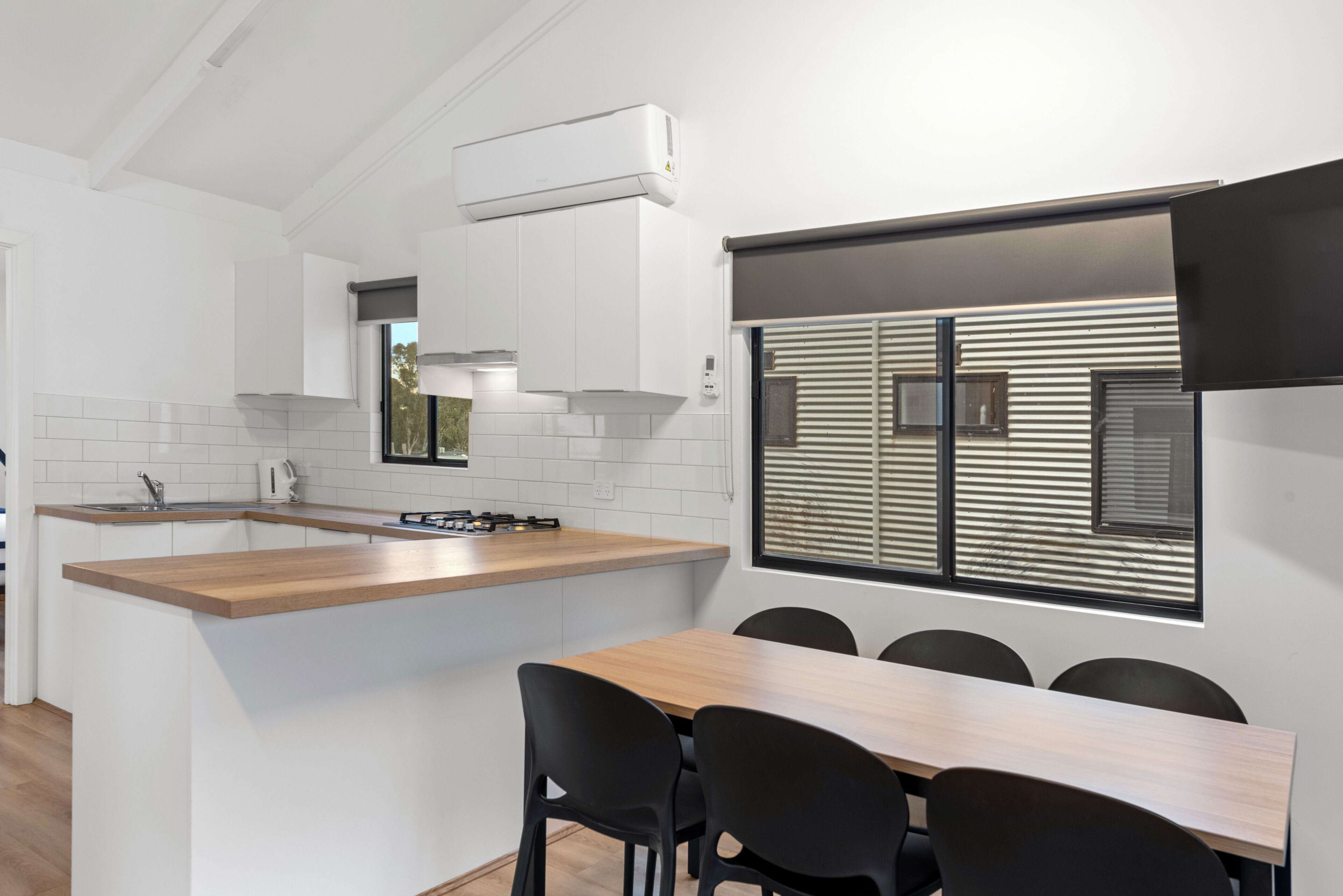 Une cuisine moderne avec des meubles blancs, un plan de travail en bois et un îlot central intégré avec des sièges.