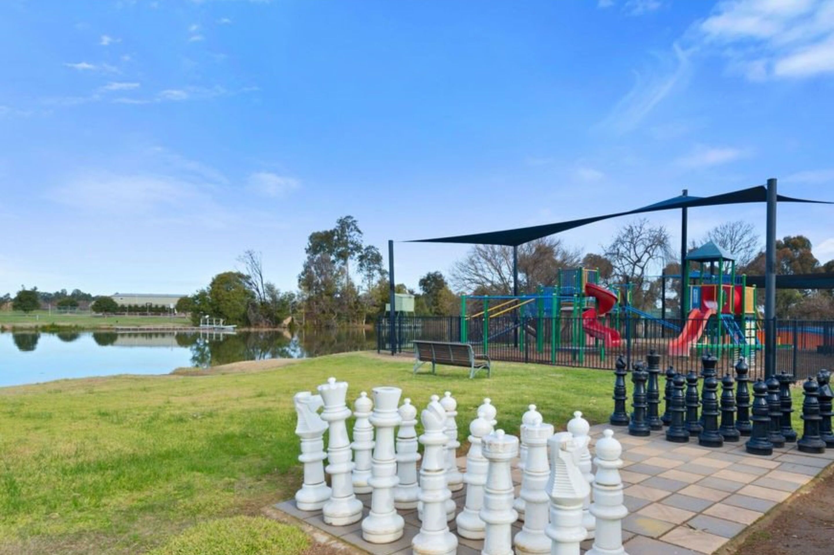 A park with a chessboard, playground, and a lake.