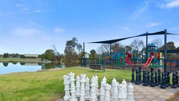 A park with a chessboard, playground, and a lake.
