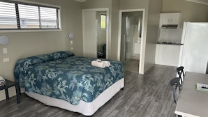 A bedroom with a bed, a desk, and a kitchenette. - Barcaldine Country Motor Inn (Barcaldine)