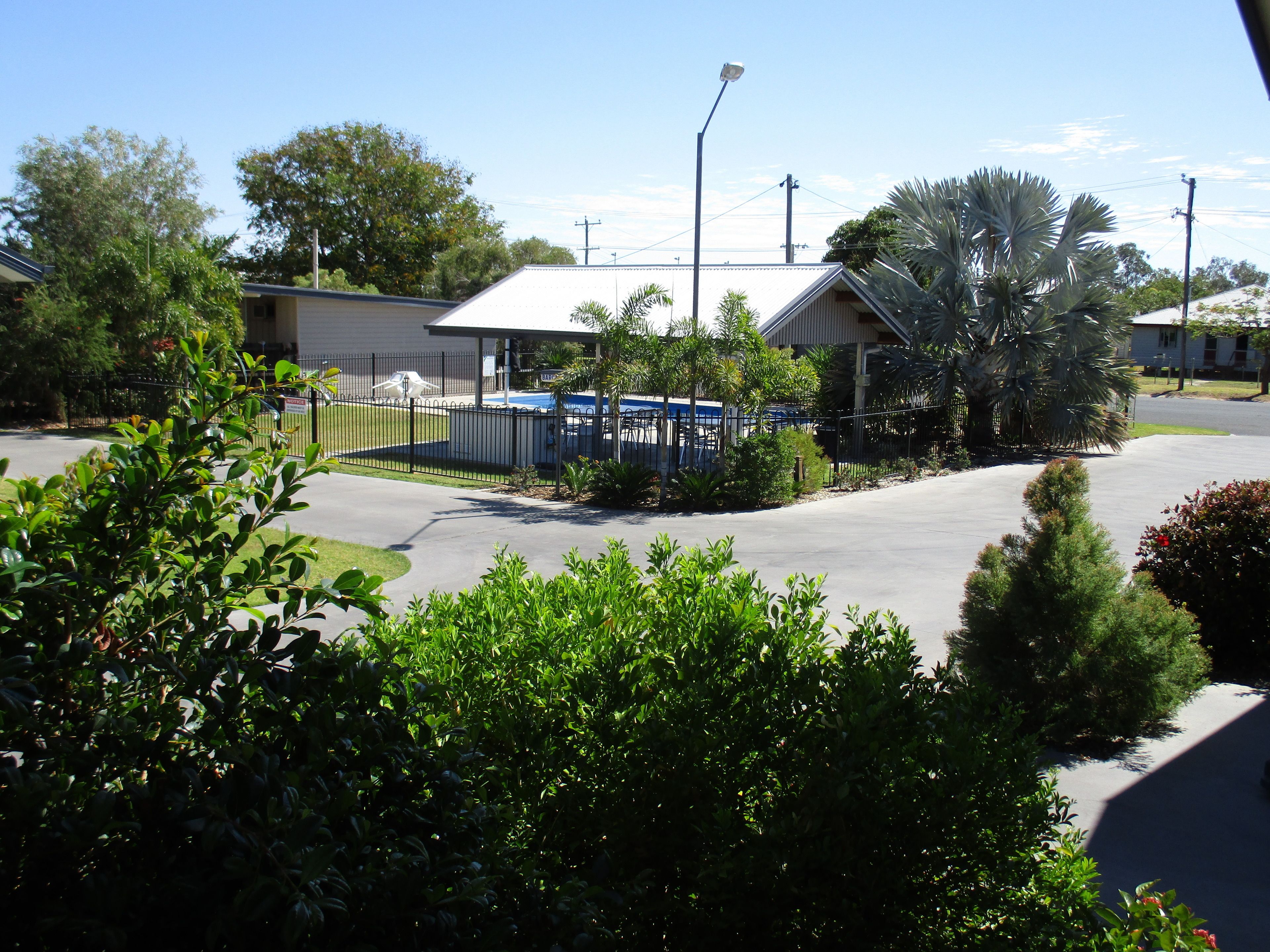 A residential area with a fenced parking lot, a building with a flat roof, and surrounding greenery.