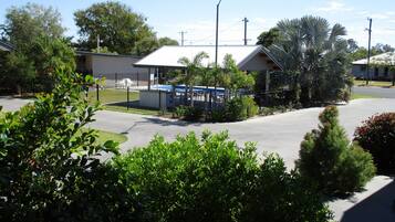A residential area with a fenced parking lot, a building with a flat roof, and surrounding greenery.