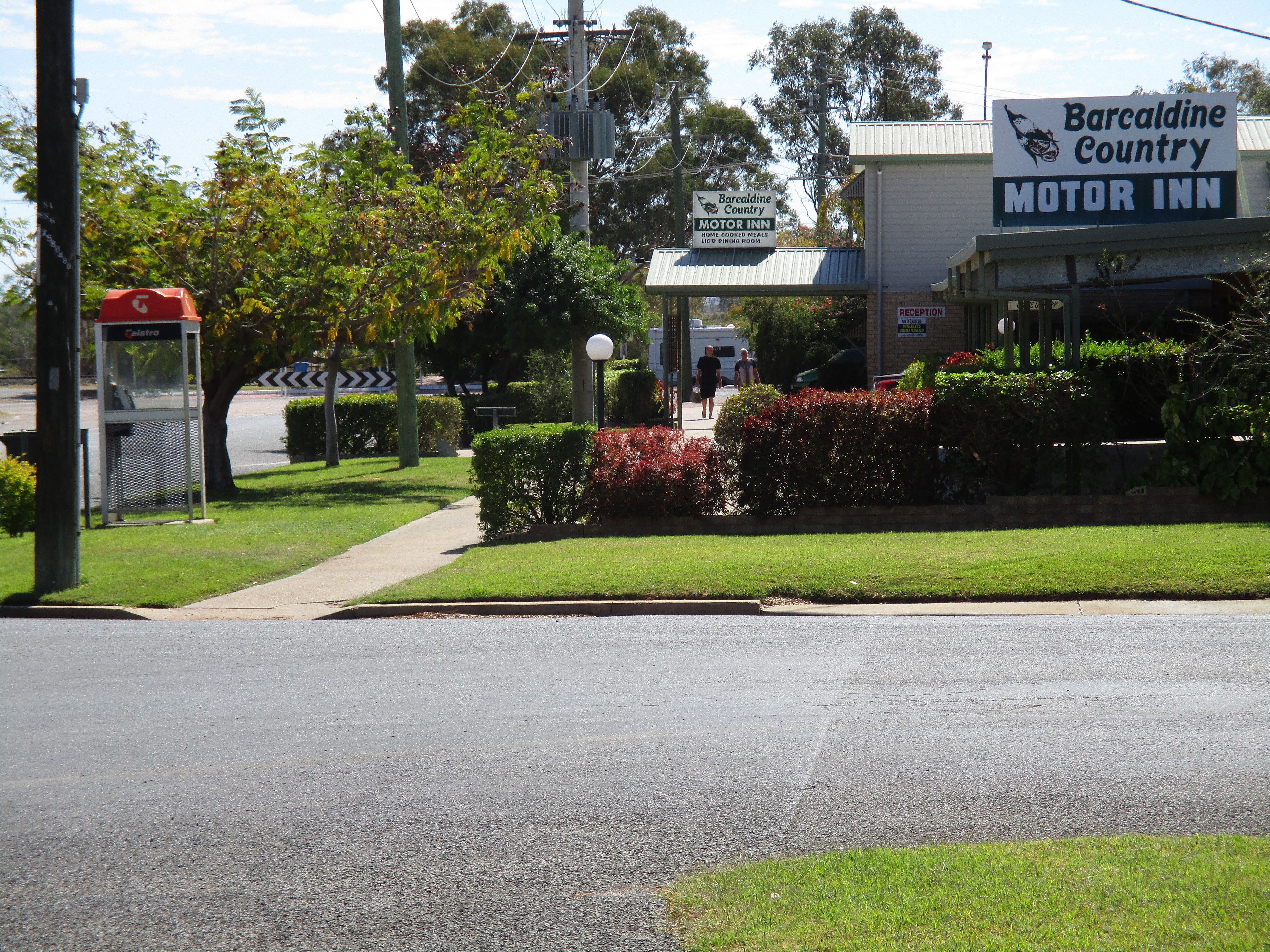 A motor inn with a signboard, a reception area, and a well-maintained lawn.