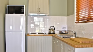 A kitchen with white cabinets, a wooden countertop, a white refrigerator, and a kettle on the stove. - Barcaldine Country Motor Inn (Barcaldine)
