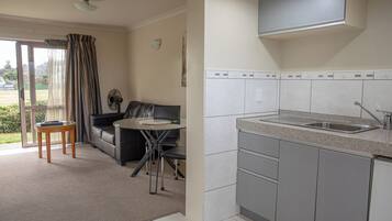 A compact living space with a kitchenette, a dining area with a table and chairs, and a sofa.